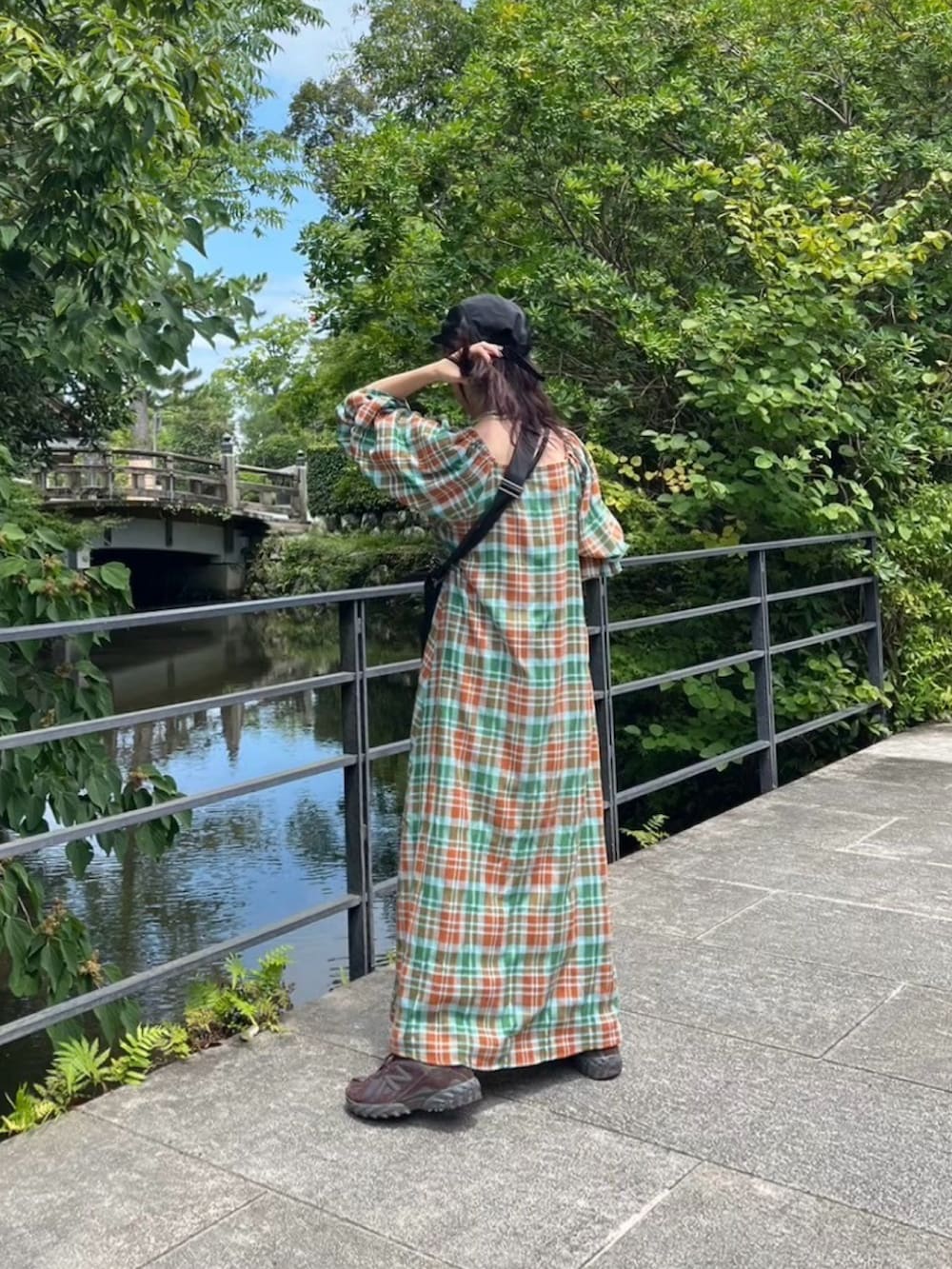 オレンジ系のワンピース、ブラック系のショルダーバッグ、ブラウン系のスニーカーを着用したレディースの秋コーディネートの2枚目の写真