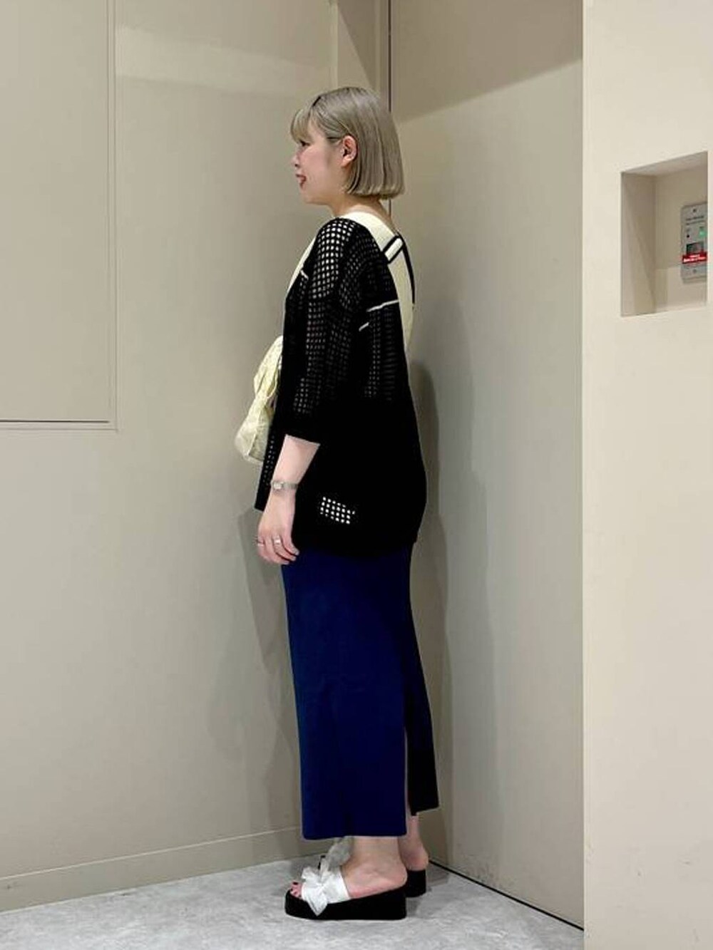 ブルー系のスカート、ホワイト系のサンダル、ブラック系のニット/セーターを着用したレディースの夏コーディネートの2枚目の写真