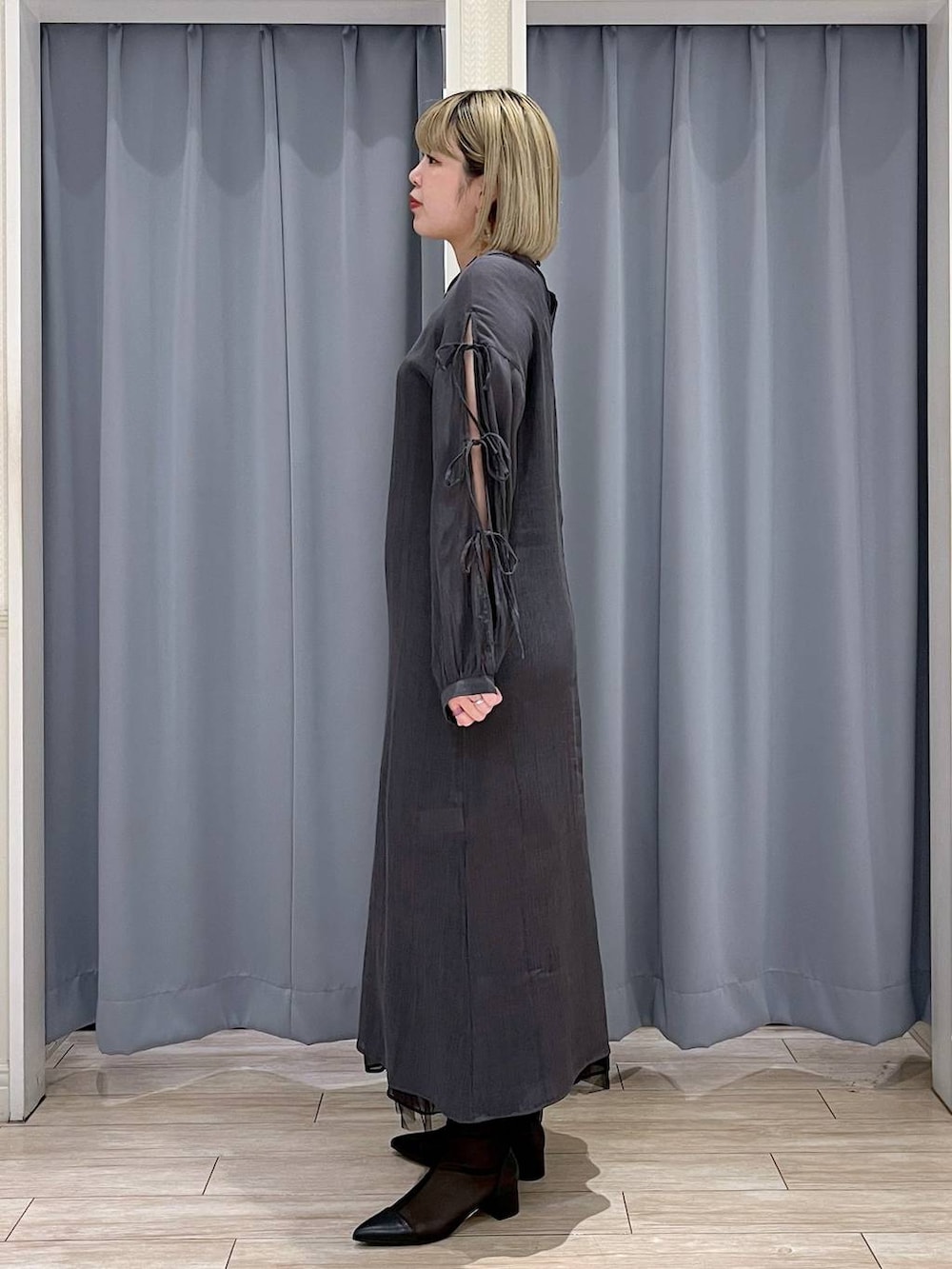 シルバー系のハンドバッグ、ブラック系のスカート、ブラック系のブーツを着用したレディースの春コーディネートの2枚目の写真