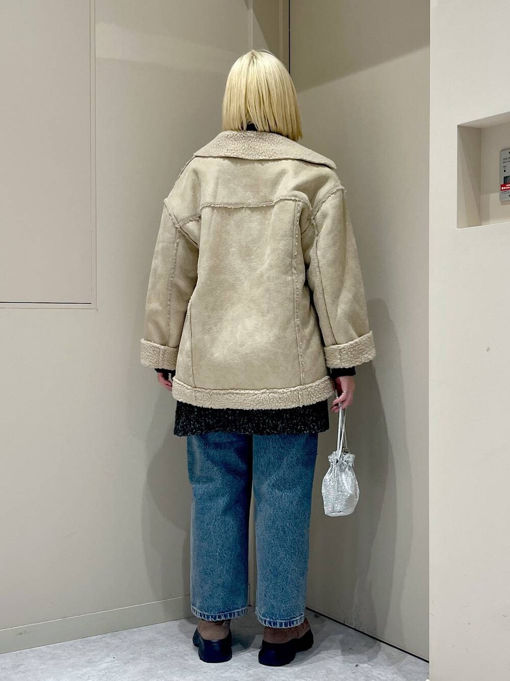 ベージュ系のブルゾン、シルバー系のショルダーバッグ、ブラウン系のモカシン/デッキシューズを着用したレディースの冬コーディネートの3枚目の写真