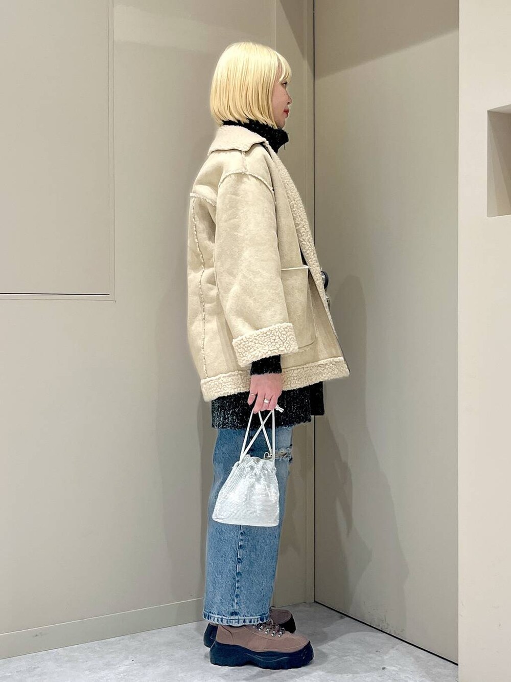 ベージュ系のブルゾン、シルバー系のショルダーバッグ、ブラウン系のモカシン/デッキシューズを着用したレディースの冬コーディネートの2枚目の写真