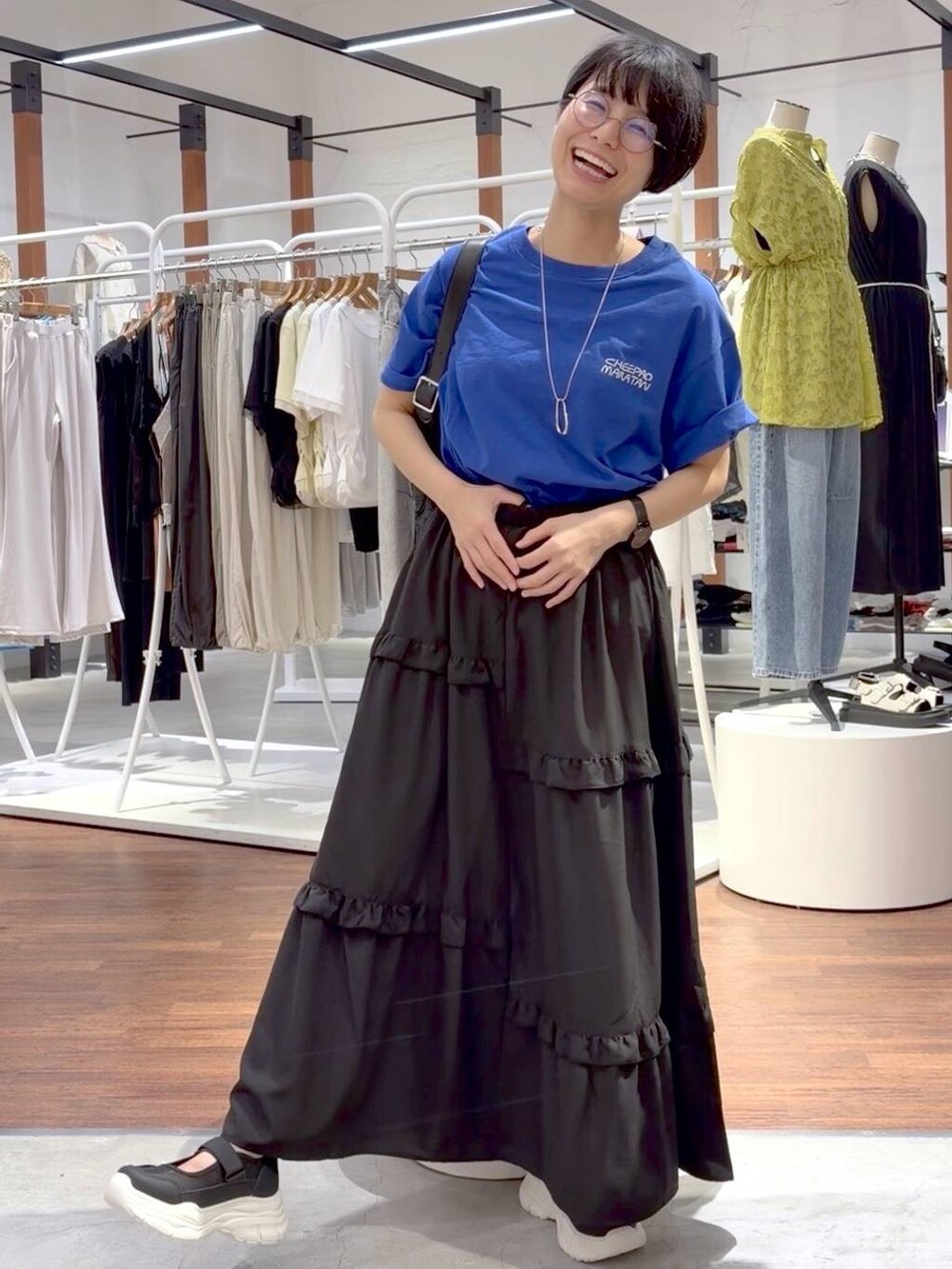 ブラック系のショルダーバッグ、ホワイト系のスニーカー、ブルー系のTシャツ/カットソーを着用したレディースの夏コーディネートの6枚目の写真