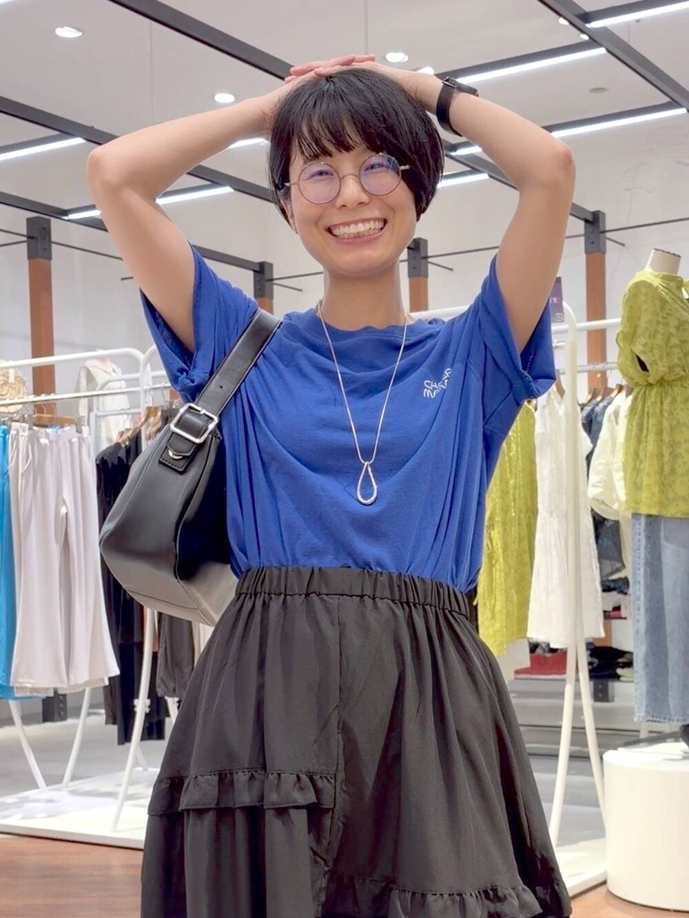 ブラック系のショルダーバッグ、ホワイト系のスニーカー、ブルー系のTシャツ/カットソーを着用したレディースの夏コーディネートの9枚目の写真