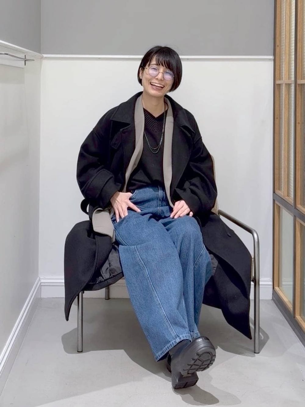 ブラック系のニット/セーター、ブラック系のステンカラーコート、ブラック系のブーツを着用したレディースの冬コーディネートの4枚目の写真