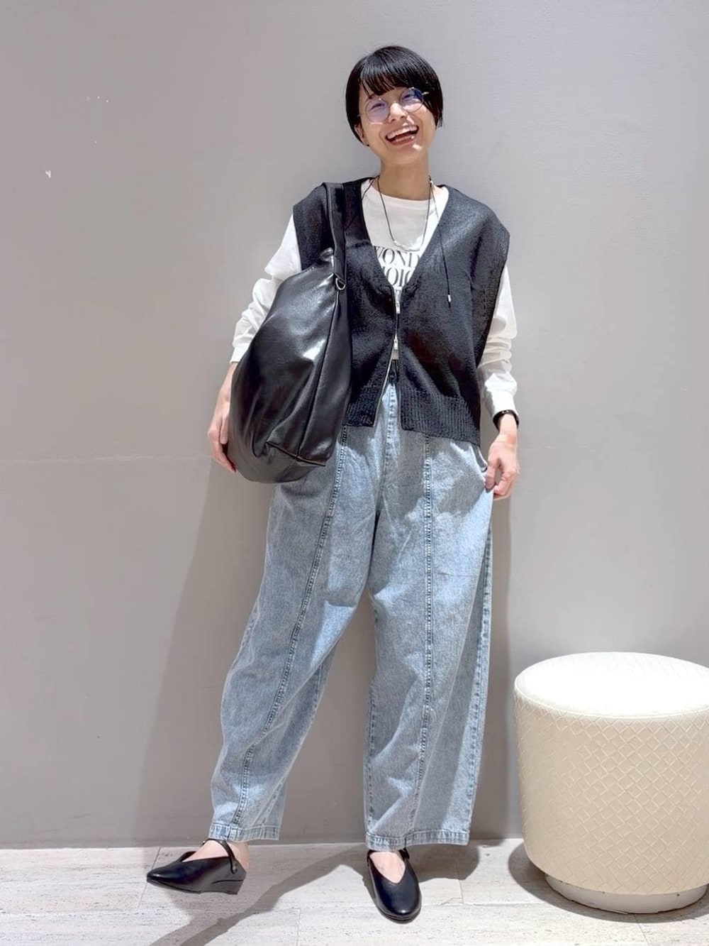 ブラック系のショルダーバッグ、ブラック系のパンプス、グレー系のベストを着用したレディースの春コーディネートの2枚目の写真