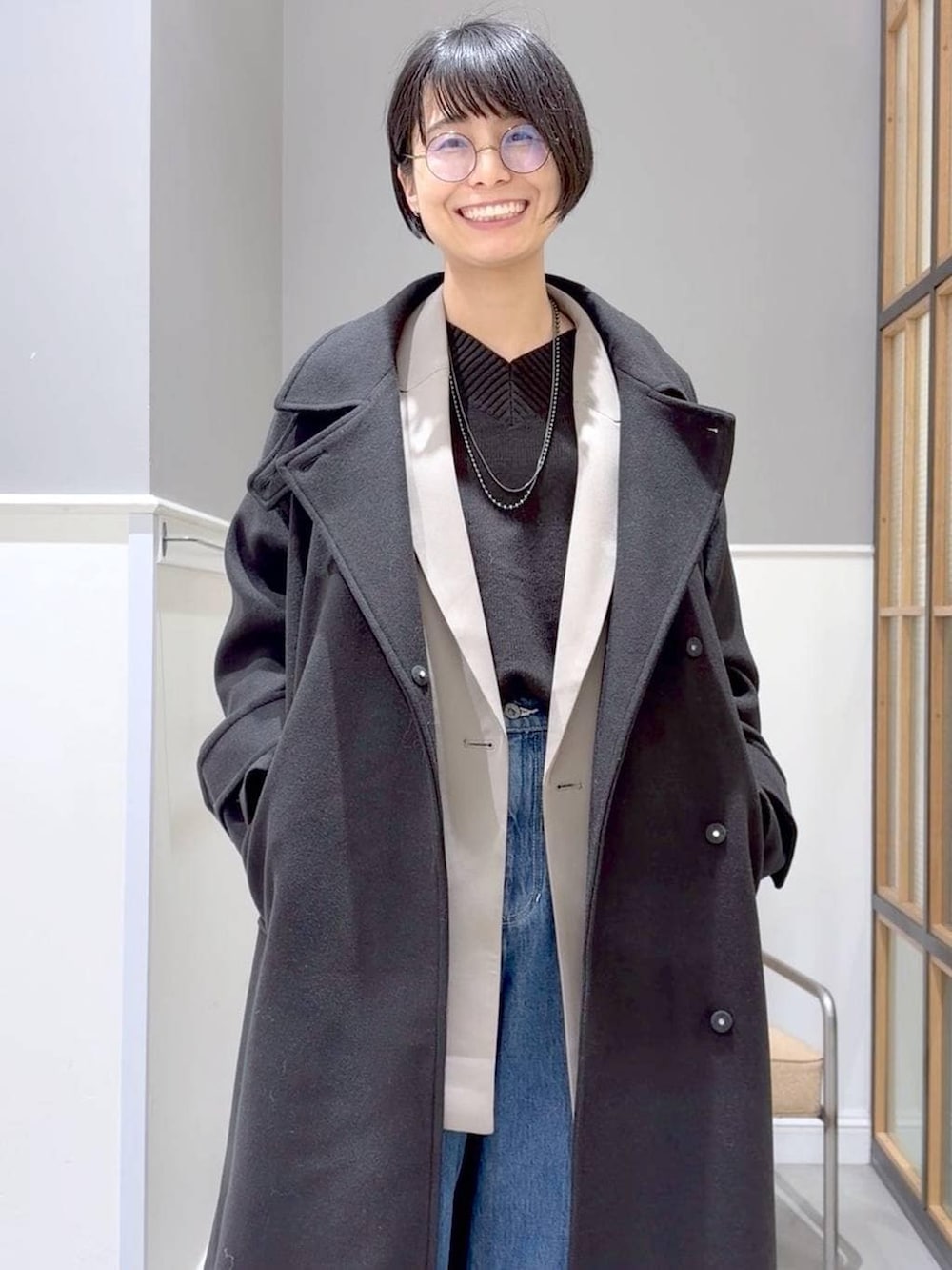 ブラック系のニット/セーター、ブラック系のステンカラーコート、ブラック系のブーツを着用したレディースの冬コーディネートの7枚目の写真