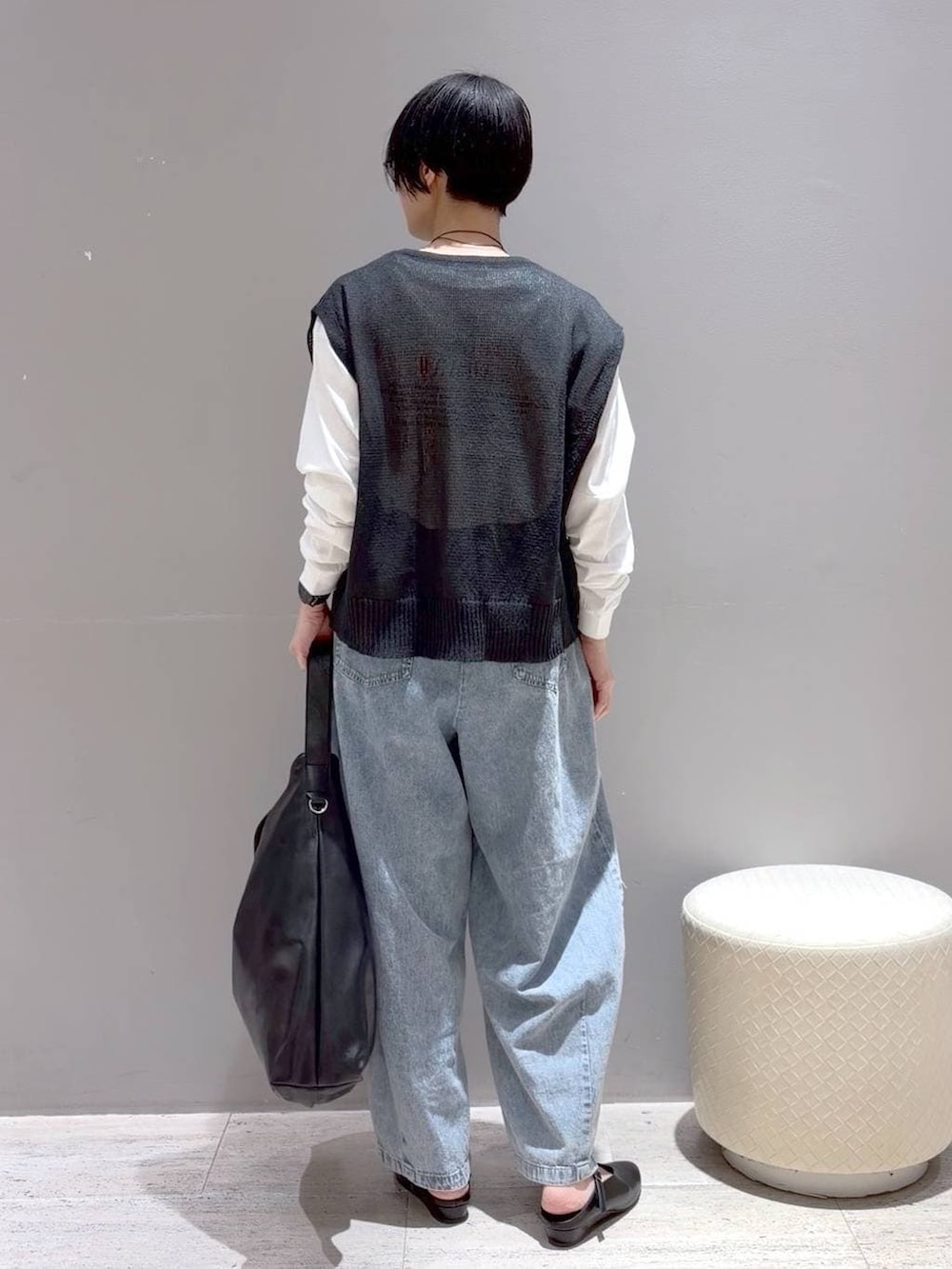 ブラック系のショルダーバッグ、ブラック系のパンプス、グレー系のベストを着用したレディースの春コーディネートの7枚目の写真