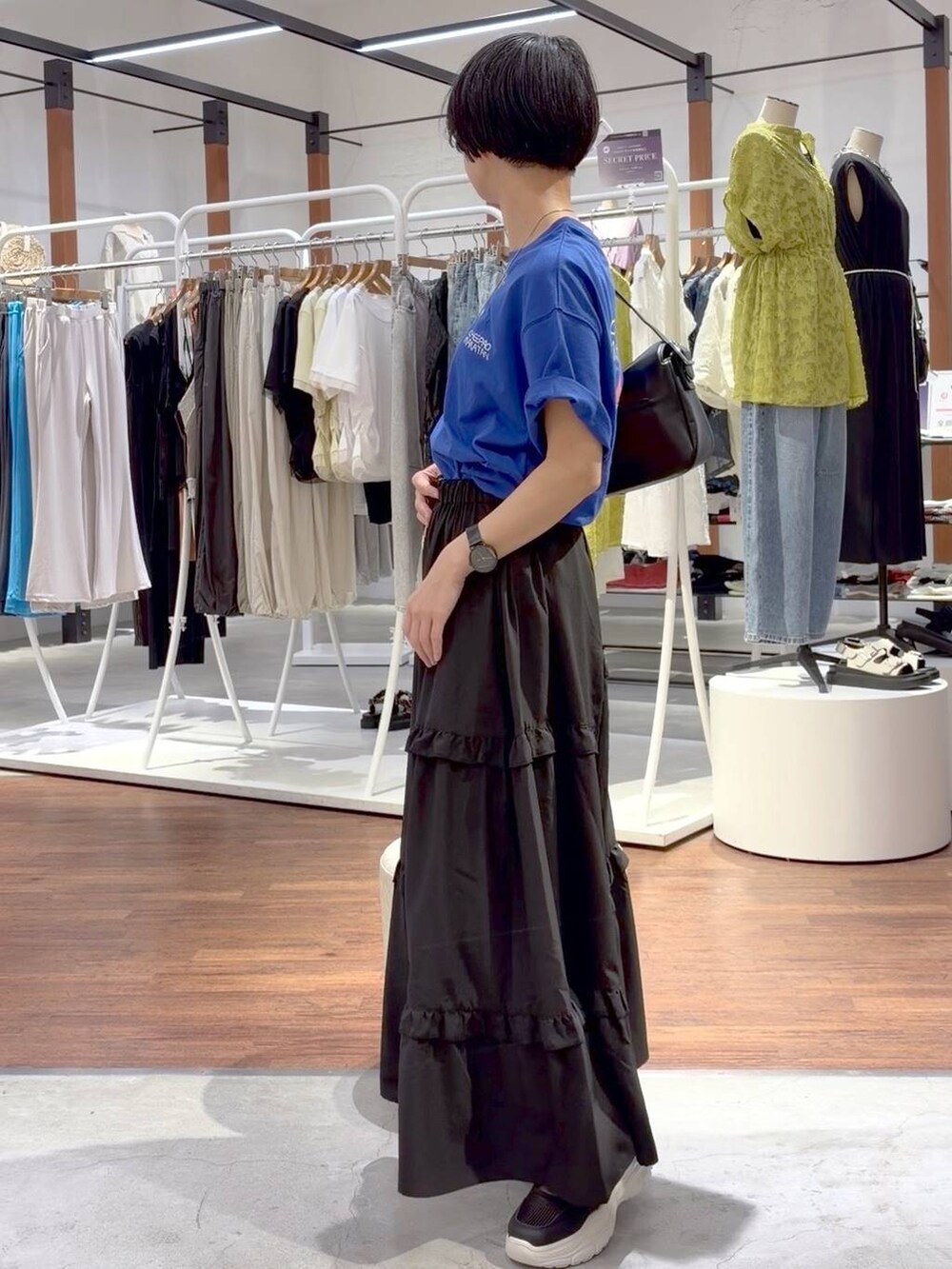 ブラック系のショルダーバッグ、ホワイト系のスニーカー、ブルー系のTシャツ/カットソーを着用したレディースの夏コーディネートの7枚目の写真