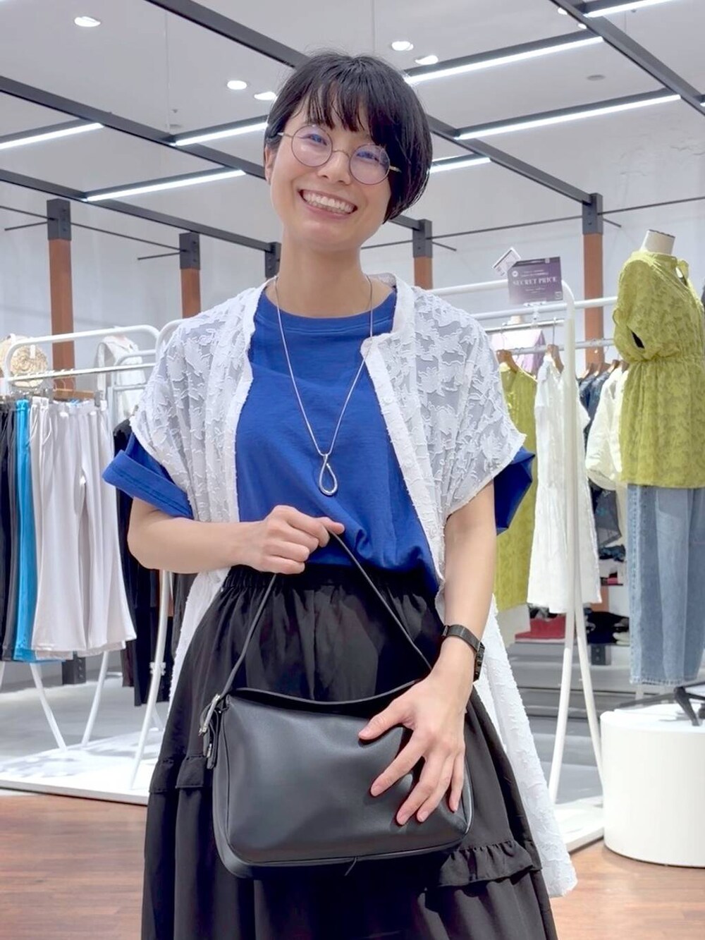 ブラック系のショルダーバッグ、ホワイト系のスニーカー、ブルー系のTシャツ/カットソーを着用したレディースの夏コーディネートの5枚目の写真