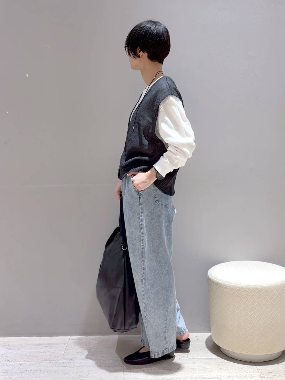 ブラック系のショルダーバッグ、ブラック系のパンプス、グレー系のベストを着用したレディースの春コーディネートの6枚目の写真