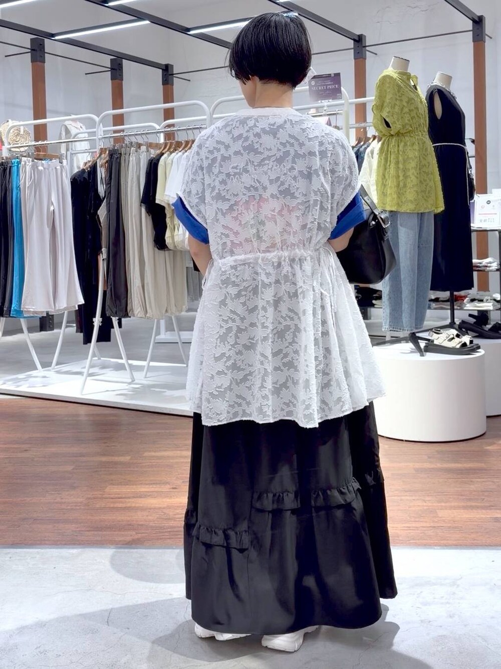 ブラック系のショルダーバッグ、ホワイト系のスニーカー、ブルー系のTシャツ/カットソーを着用したレディースの夏コーディネートの4枚目の写真
