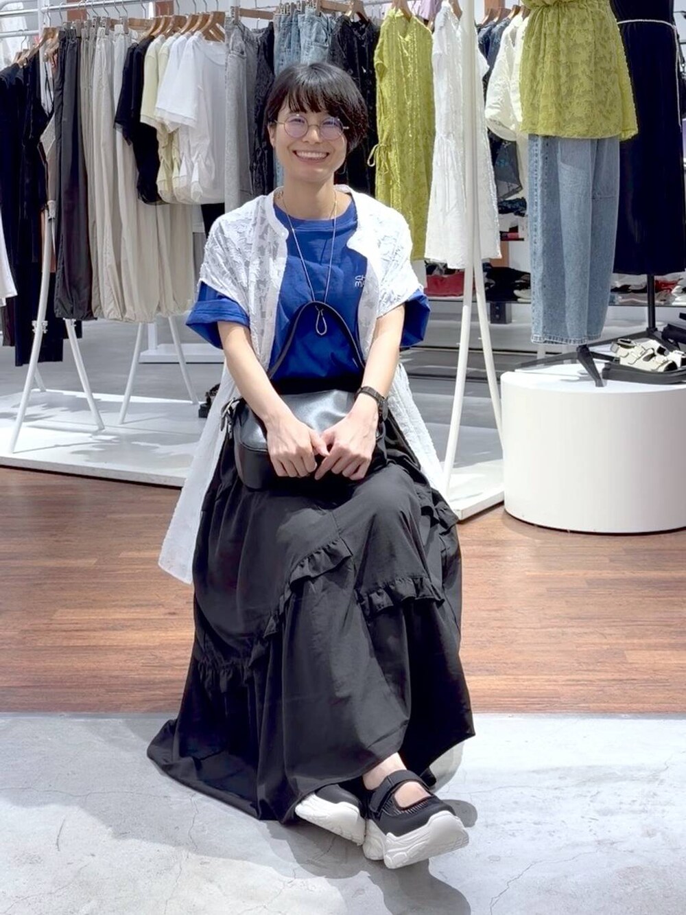 ブラック系のショルダーバッグ、ホワイト系のスニーカー、ブルー系のTシャツ/カットソーを着用したレディースの夏コーディネートの2枚目の写真