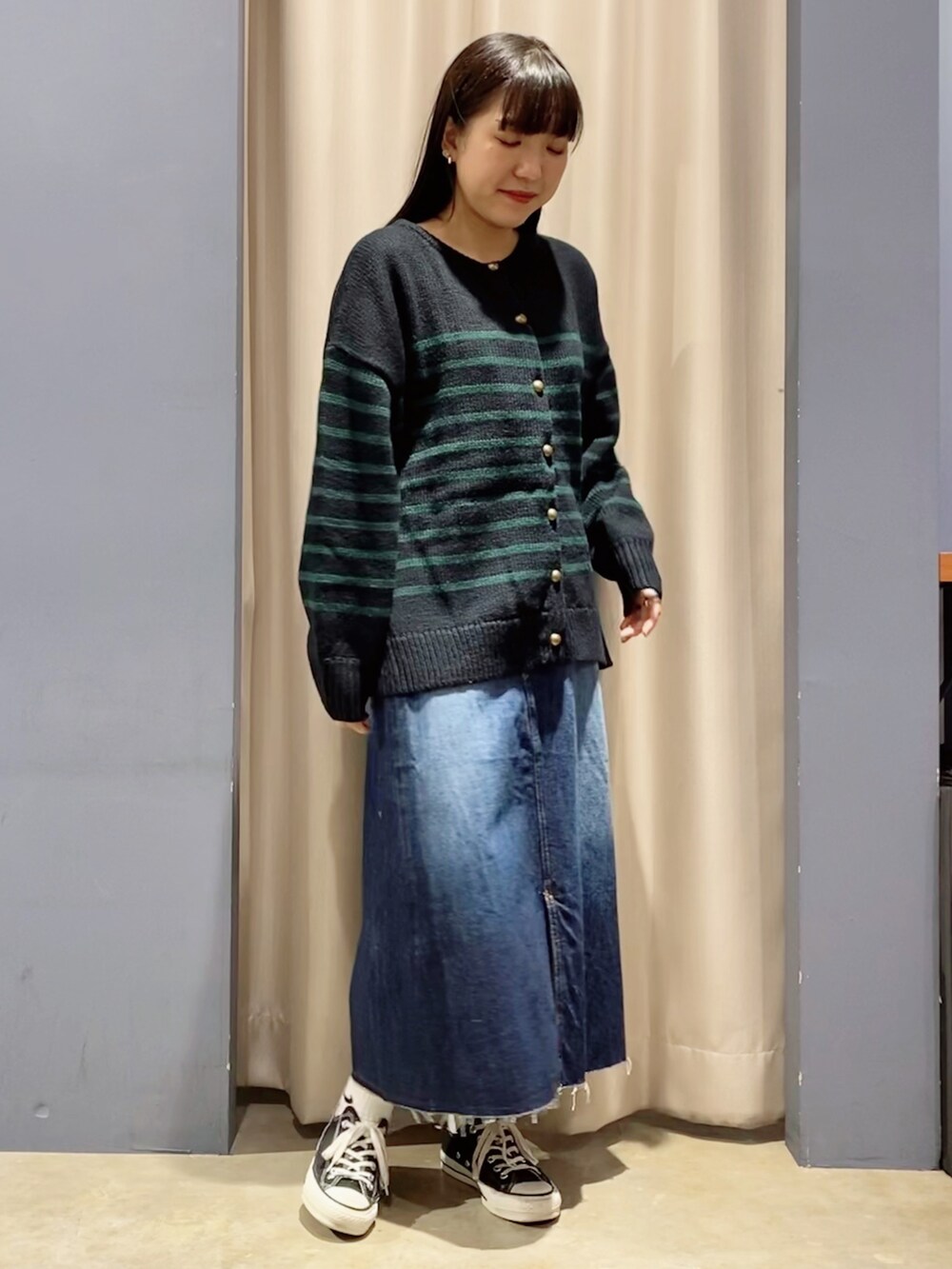 ブルー系のカーディガン/ボレロ、ブルー系のデニムスカート、ブラック系のスニーカーを着用したレディースの秋コーディネートの2枚目の写真