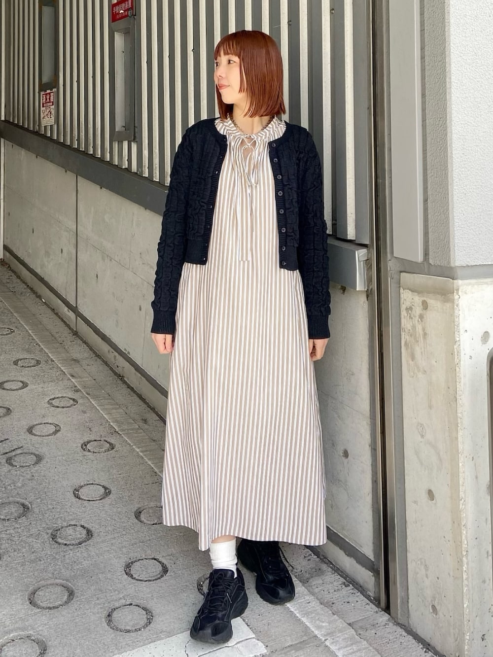 ベージュ系のシャツワンピース、ブラック系のカーディガン/ボレロを着用したレディースの春コーディネートの2枚目の写真