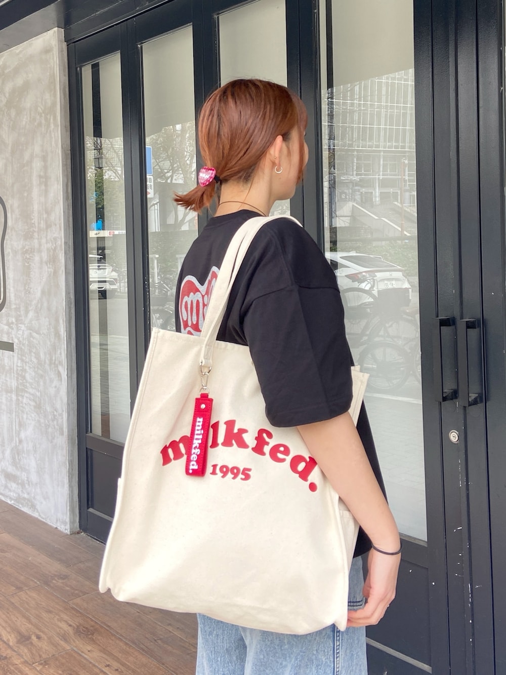 ブラック系のTシャツ/カットソー、ブルー系のデニムパンツ、レッド系のヘアゴムを着用したレディースの春コーディネートの6枚目の写真