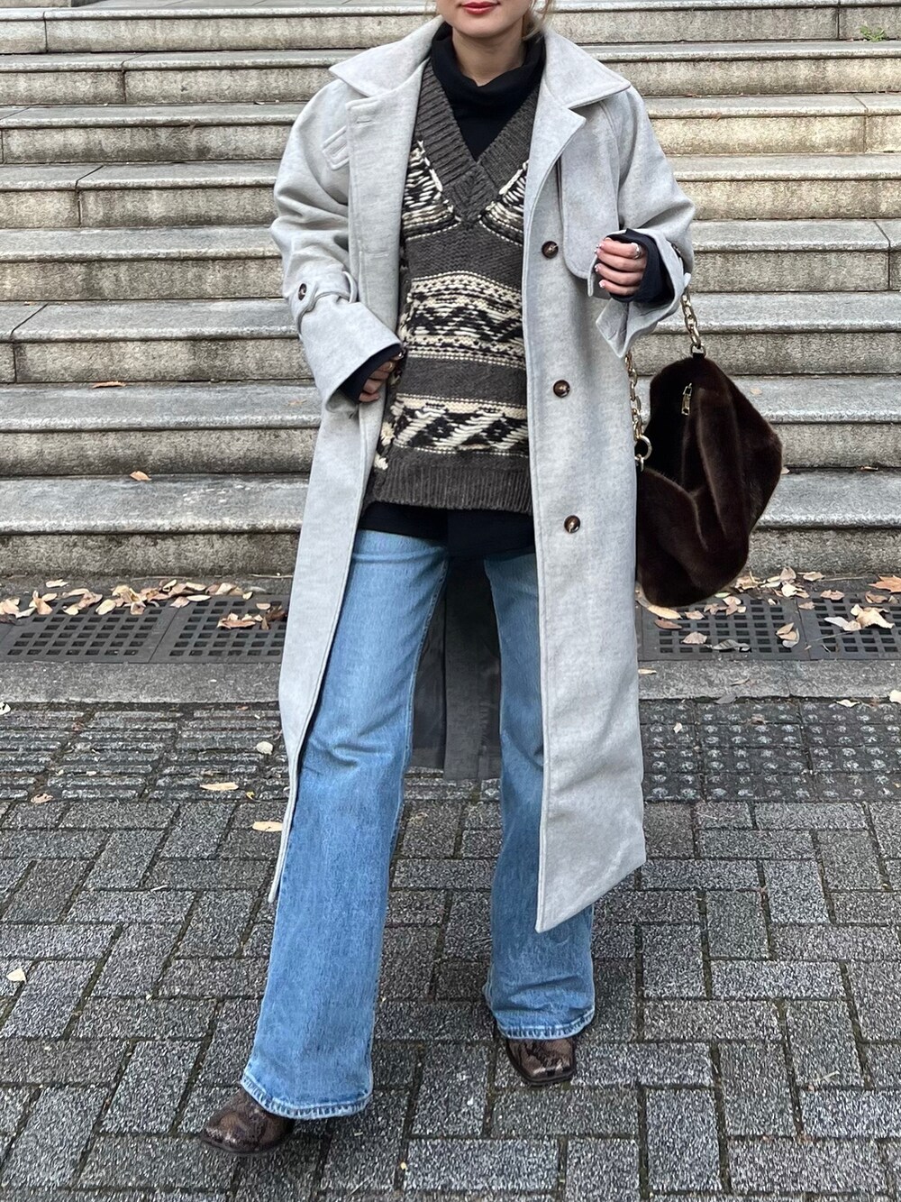 ベージュ系のトレンチコート、ブラウン系のニット/セーター、ブラウン系のバッグを着用したレディースの冬コーディネートの2枚目の写真