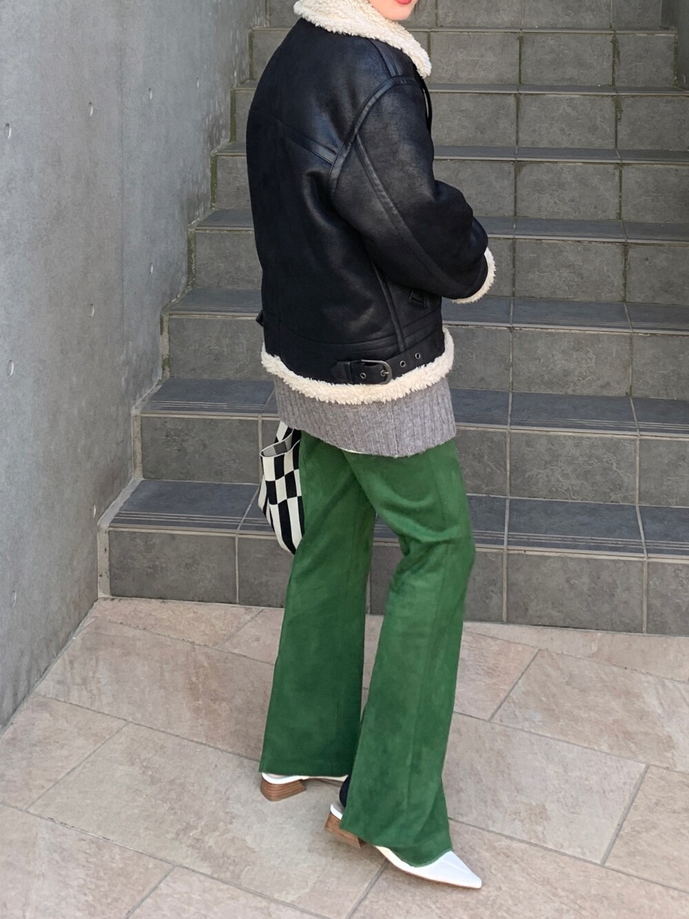 ブラック系のブルゾン、グレー系のカーディガン/ボレロ、ホワイト系のトートバッグを着用したレディースの冬コーディネートの3枚目の写真