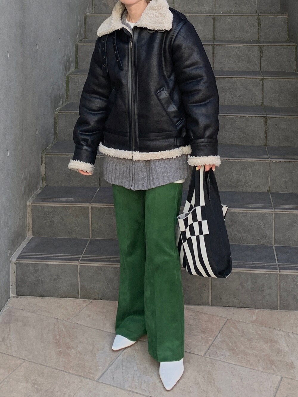 ブラック系のブルゾン、グレー系のカーディガン/ボレロ、ホワイト系のトートバッグを着用したレディースの冬コーディネートの2枚目の写真