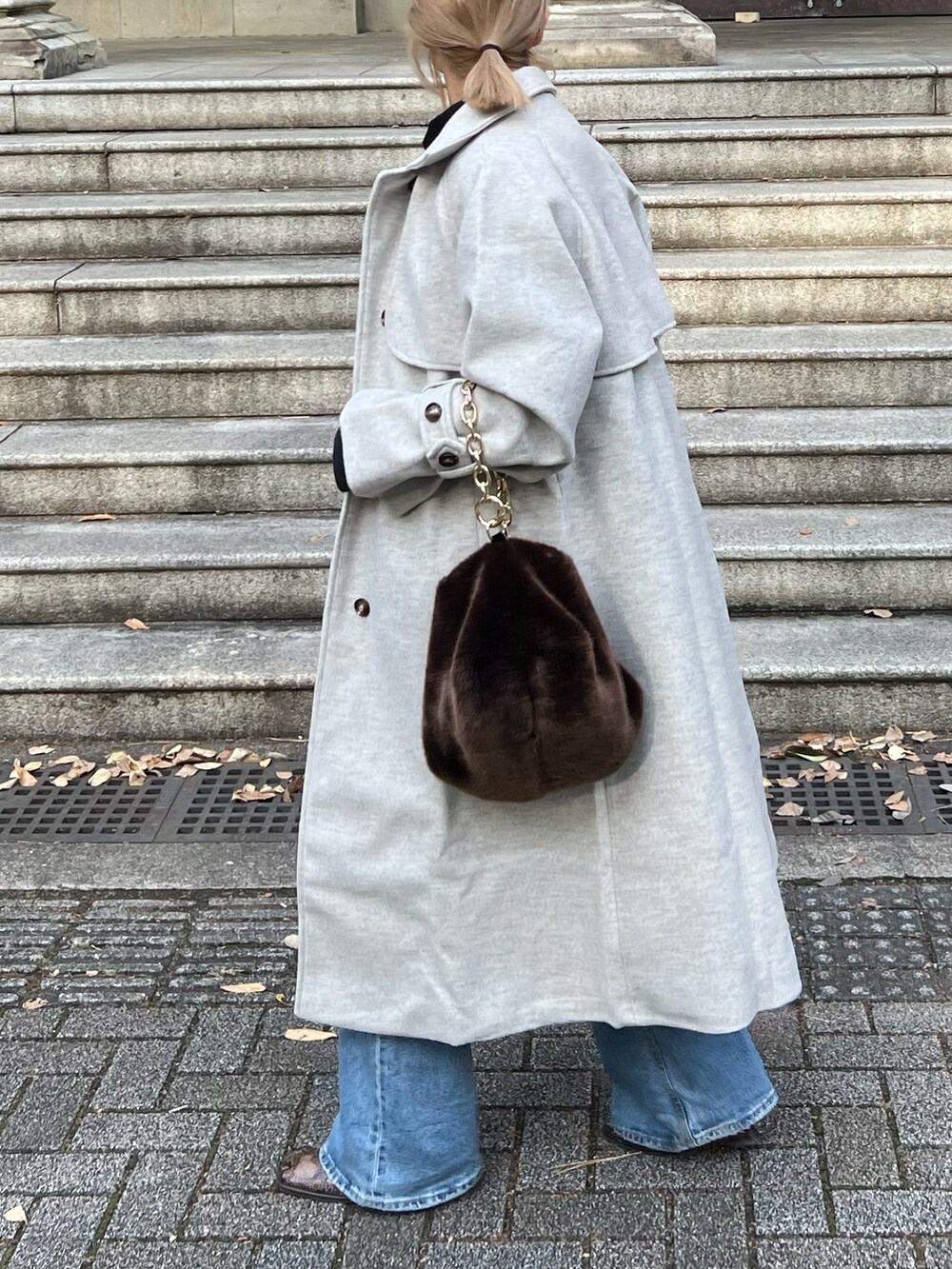 ベージュ系のトレンチコート、ブラウン系のニット/セーター、ブラウン系のバッグを着用したレディースの冬コーディネートの4枚目の写真