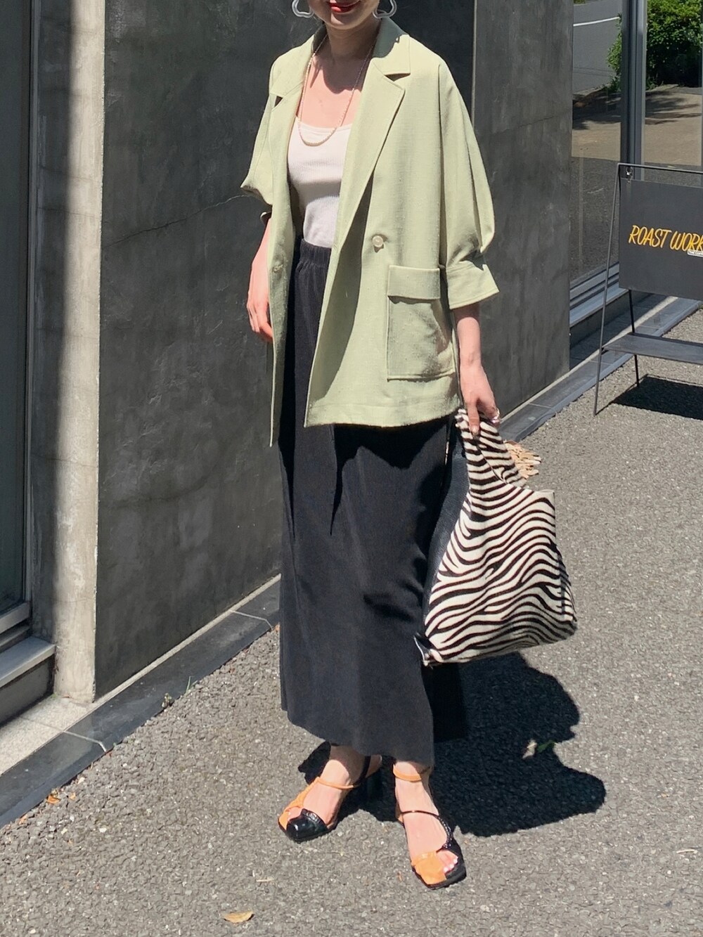 グリーン系のナイロンジャケット、ブラック系のスカート、ホワイト系のトートバッグを着用したレディースの夏コーディネートの2枚目の写真