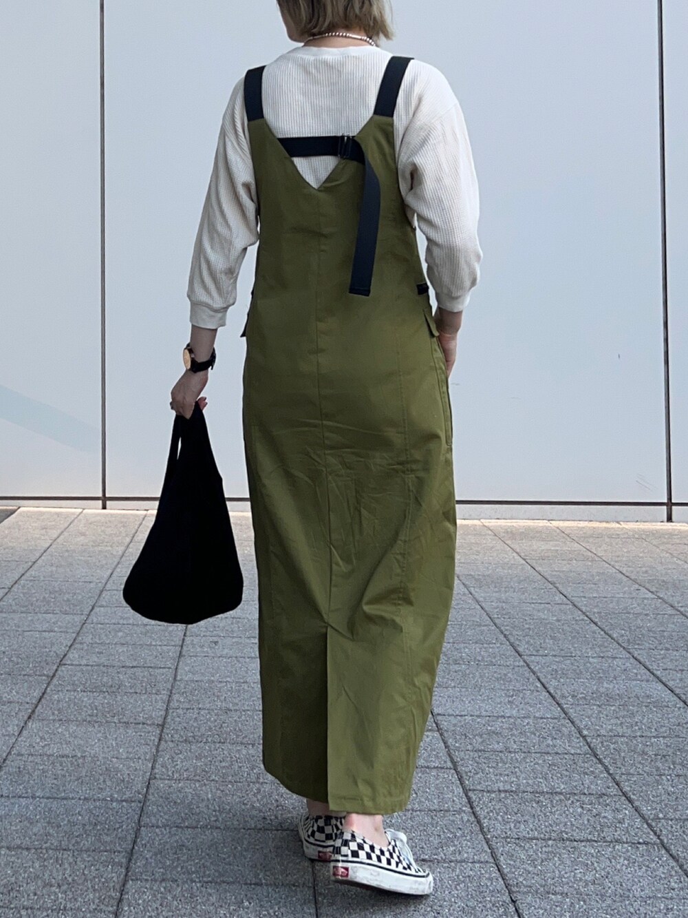 グリーン系のジャンパースカート、ホワイト系のTシャツ/カットソー、ブラック系のスニーカーを着用したレディースの夏コーディネートの4枚目の写真