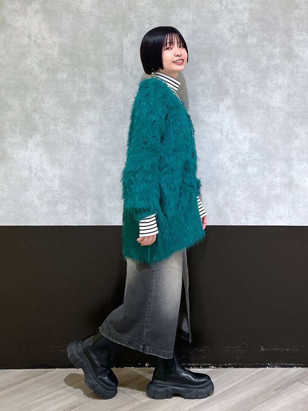 ブラック系のブーツ、グリーン系のカーディガン/ボレロ、ブラック系のスカートを着用したレディースの秋コーディネートの4枚目の写真