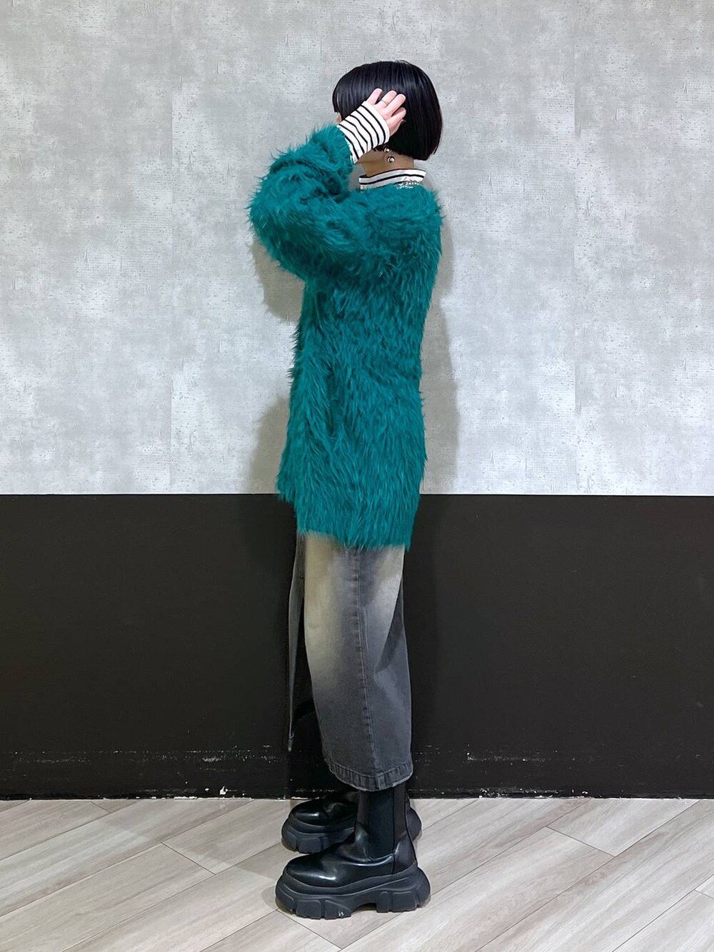 ブラック系のブーツ、グリーン系のカーディガン/ボレロ、ブラック系のスカートを着用したレディースの秋コーディネートの2枚目の写真