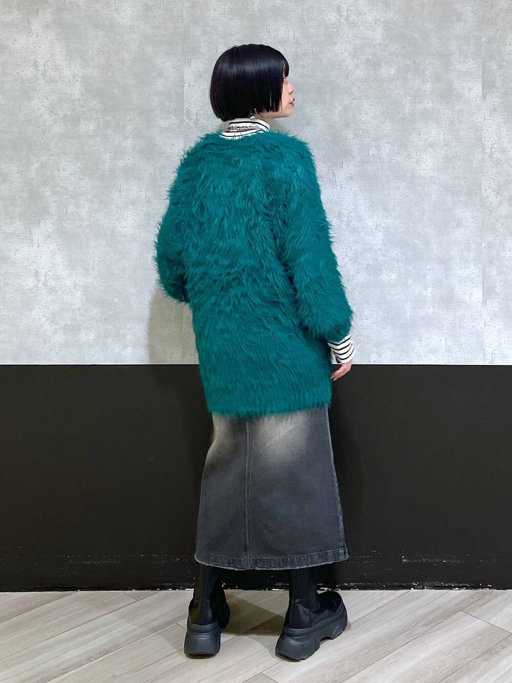 ブラック系のブーツ、グリーン系のカーディガン/ボレロ、ブラック系のスカートを着用したレディースの秋コーディネートの3枚目の写真