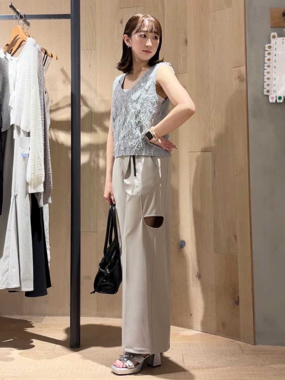 グレー系のベスト、ホワイト系のスラックスを着用したレディースの夏コーディネートの2枚目の写真