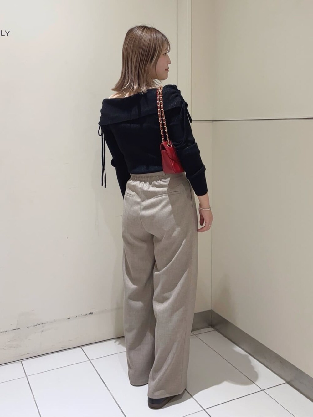 ブラック系のニット/セーター、ベージュ系のスラックス、レッド系のショルダーバッグを着用したレディースの冬コーディネートの2枚目の写真