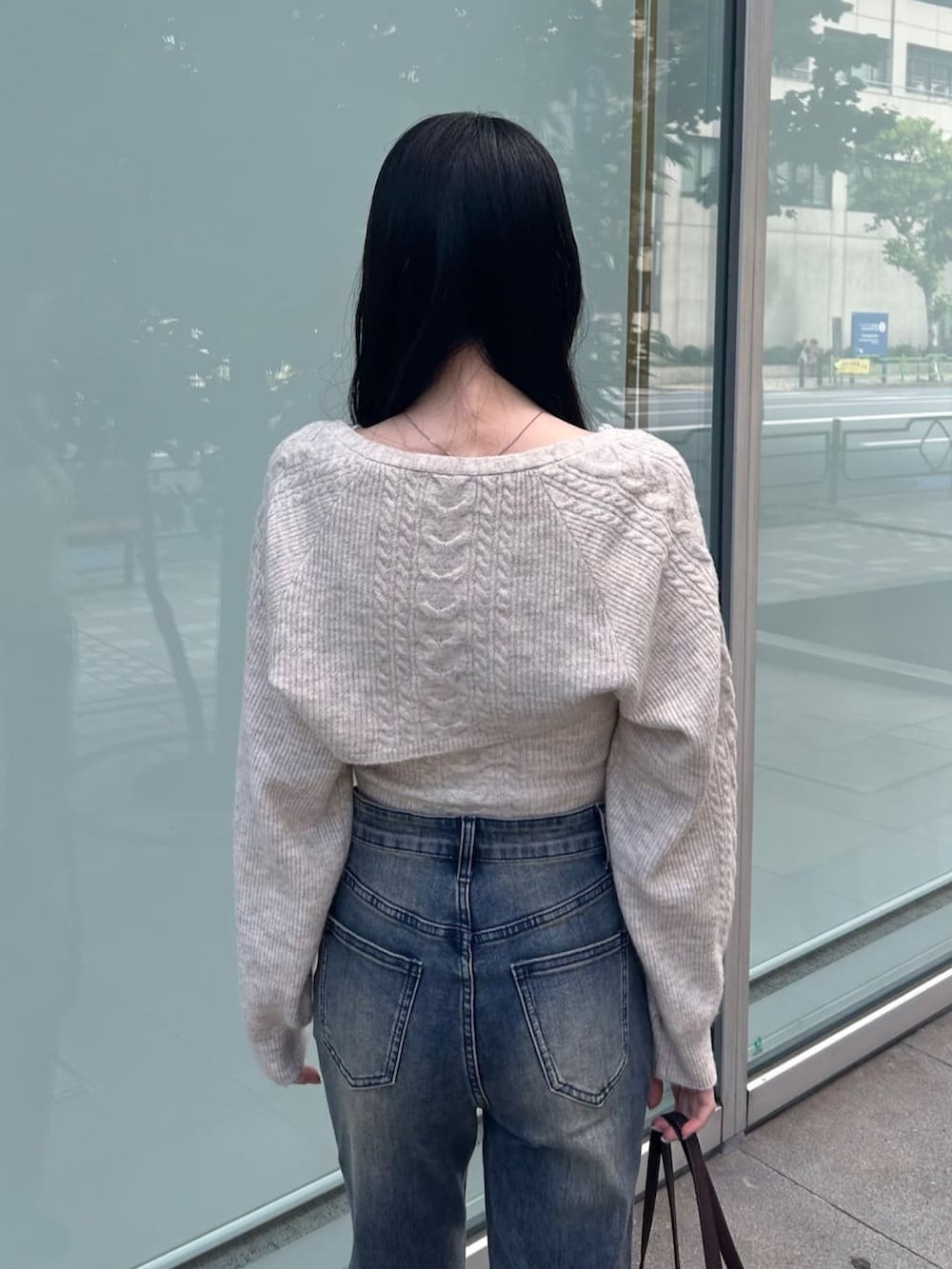 ホワイト系のアンサンブル、ブルー系のデニムパンツ、ブラック系のブーツを着用したレディースの秋コーディネートの3枚目の写真