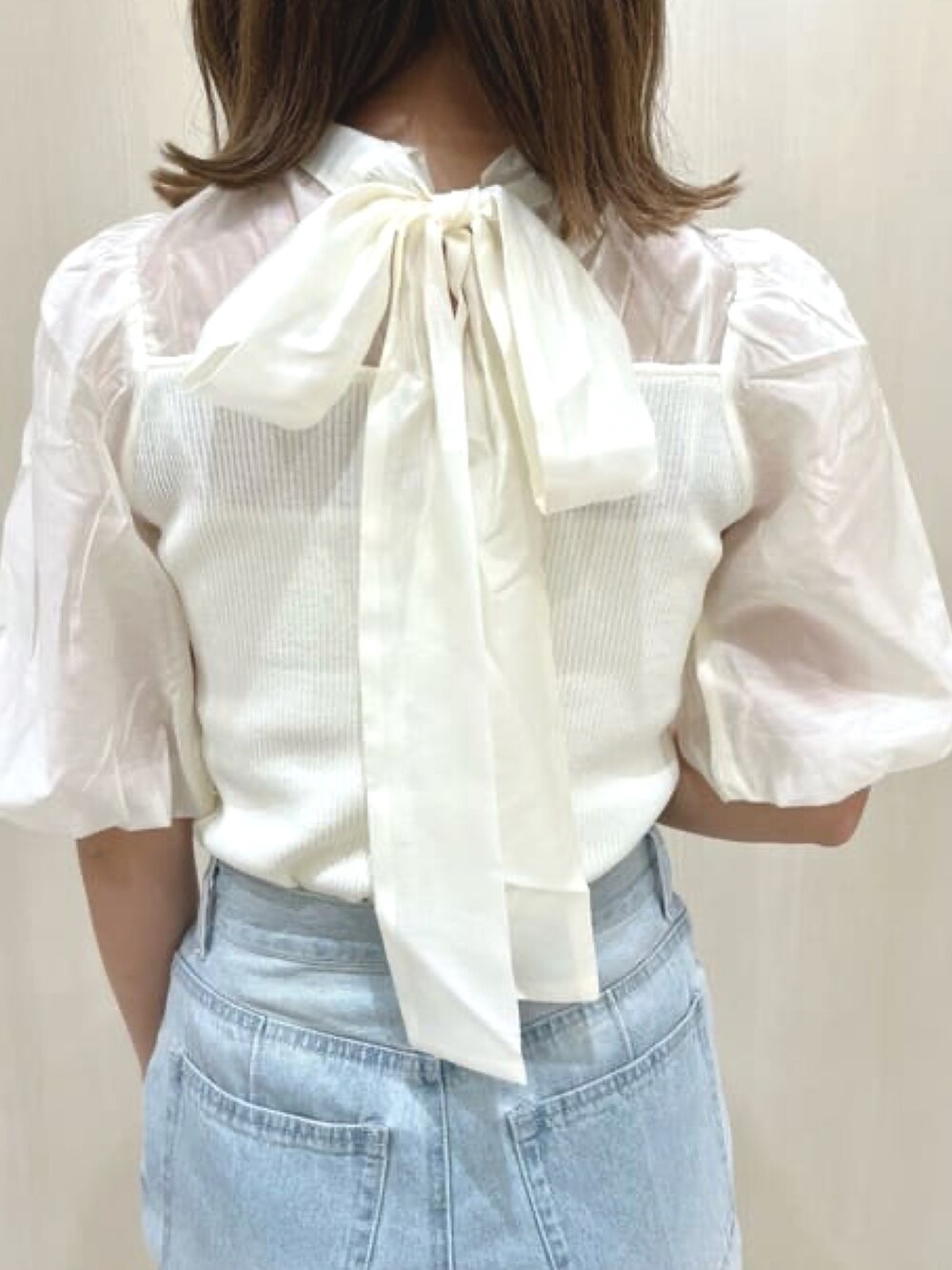 ホワイト系のニット/セーター、ブルー系のデニムパンツ、ホワイト系のサンダルを着用したレディースの春コーディネートの3枚目の写真