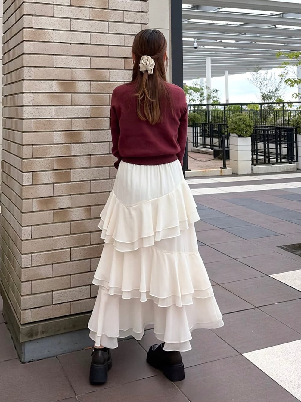レッド系のニット/セーター、ホワイト系のスカート、ホワイト系のショルダーバッグを着用したレディースの秋コーディネートの2枚目の写真