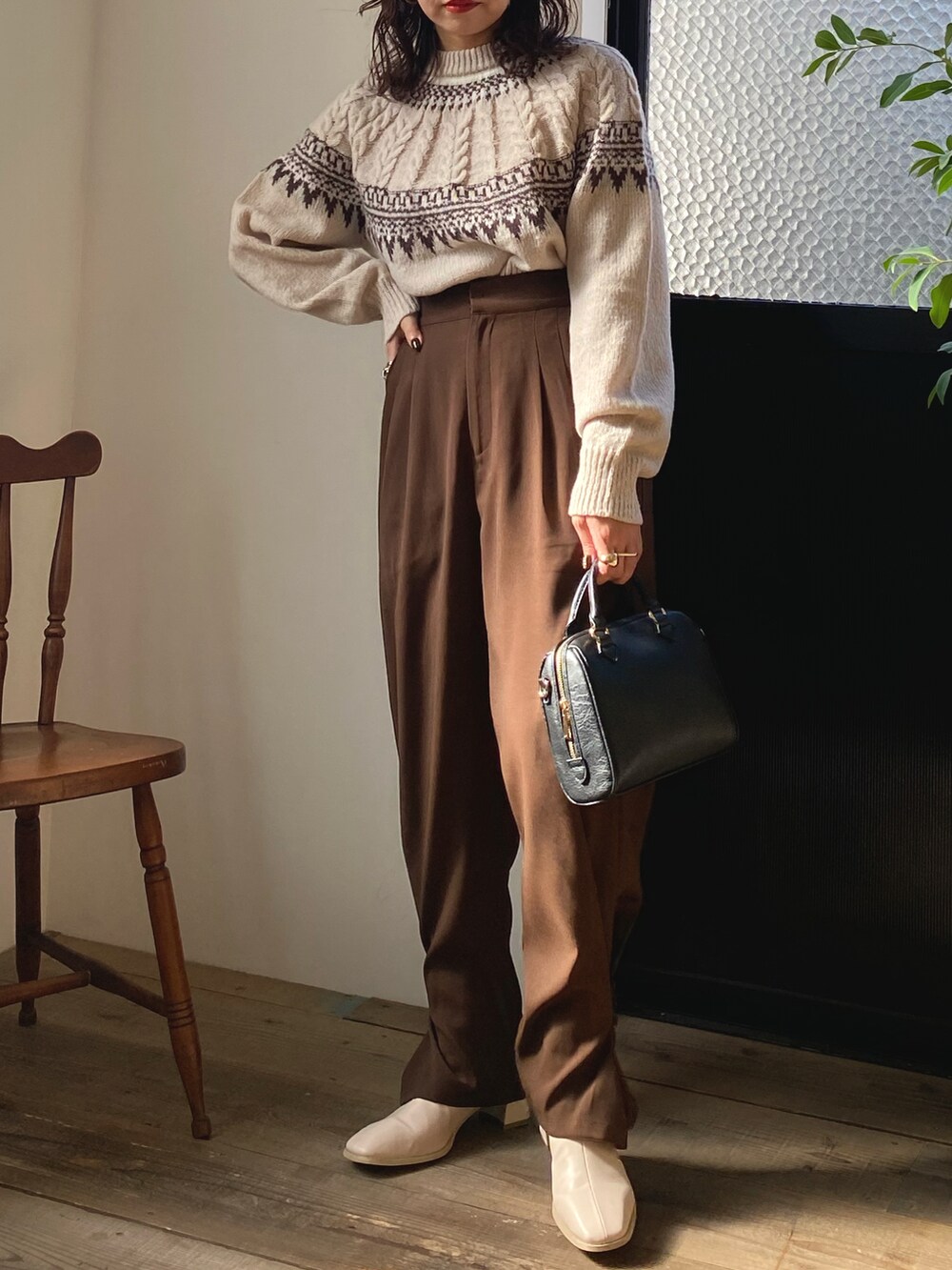 ブラック系のボストンバッグ、ホワイト系のニット/セーター、ブラウン系のその他パンツを着用したレディースの冬コーディネートの2枚目の写真