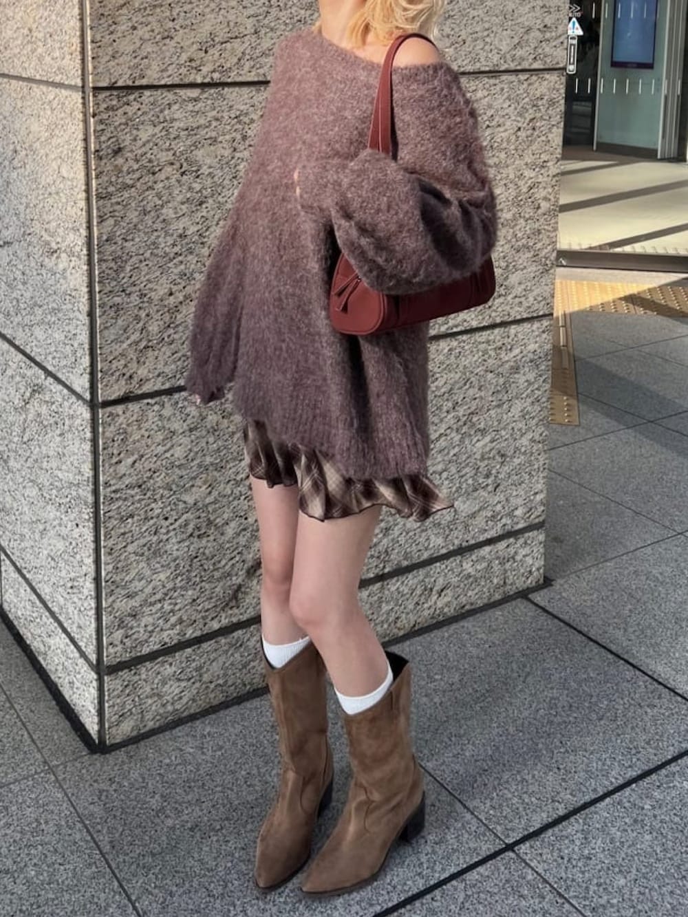 ブラウン系のニット/セーター、ブラウン系のスカート、ブラウン系のブーツを着用したレディースの秋コーディネートの2枚目の写真