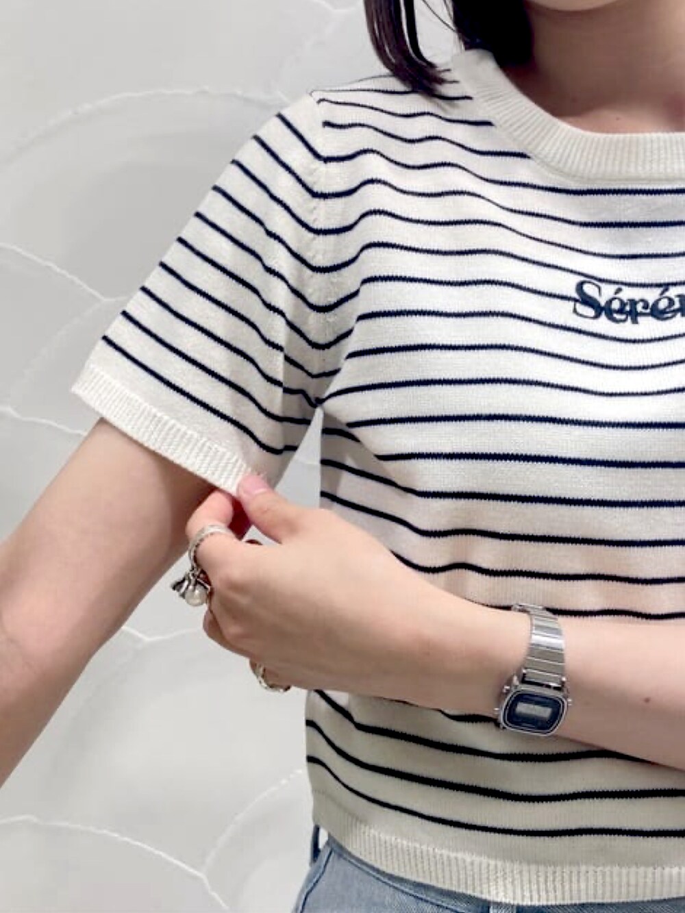 ホワイト系のニット/セーター、ブルー系のデニムパンツ、ブラック系のサンダルを着用したレディースの夏コーディネートの3枚目の写真