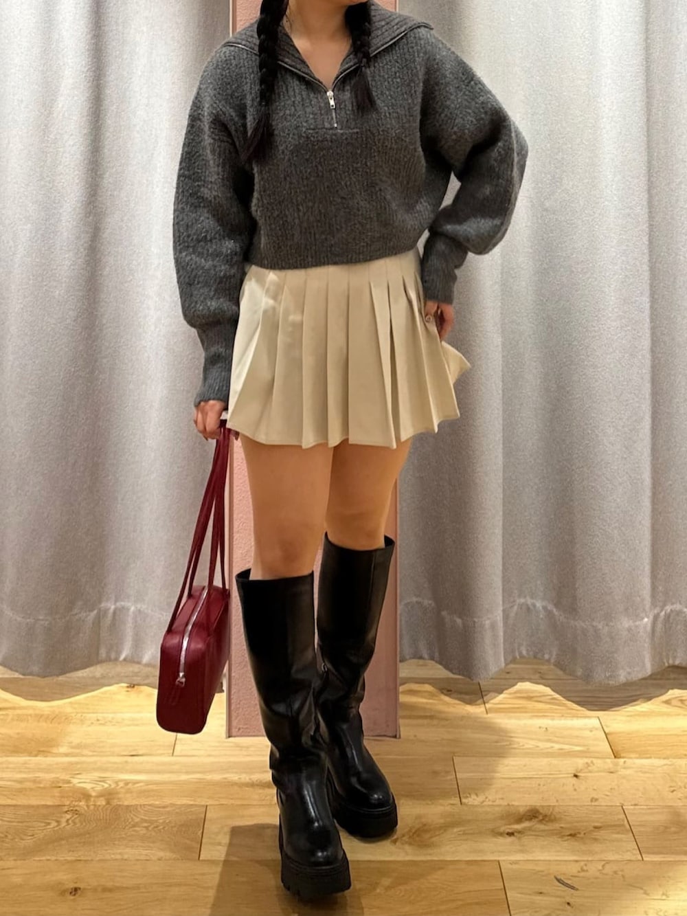 ブラック系のニット/セーター、グレー系のスカート、レッド系のショルダーバッグを着用したレディースの冬コーディネートの2枚目の写真