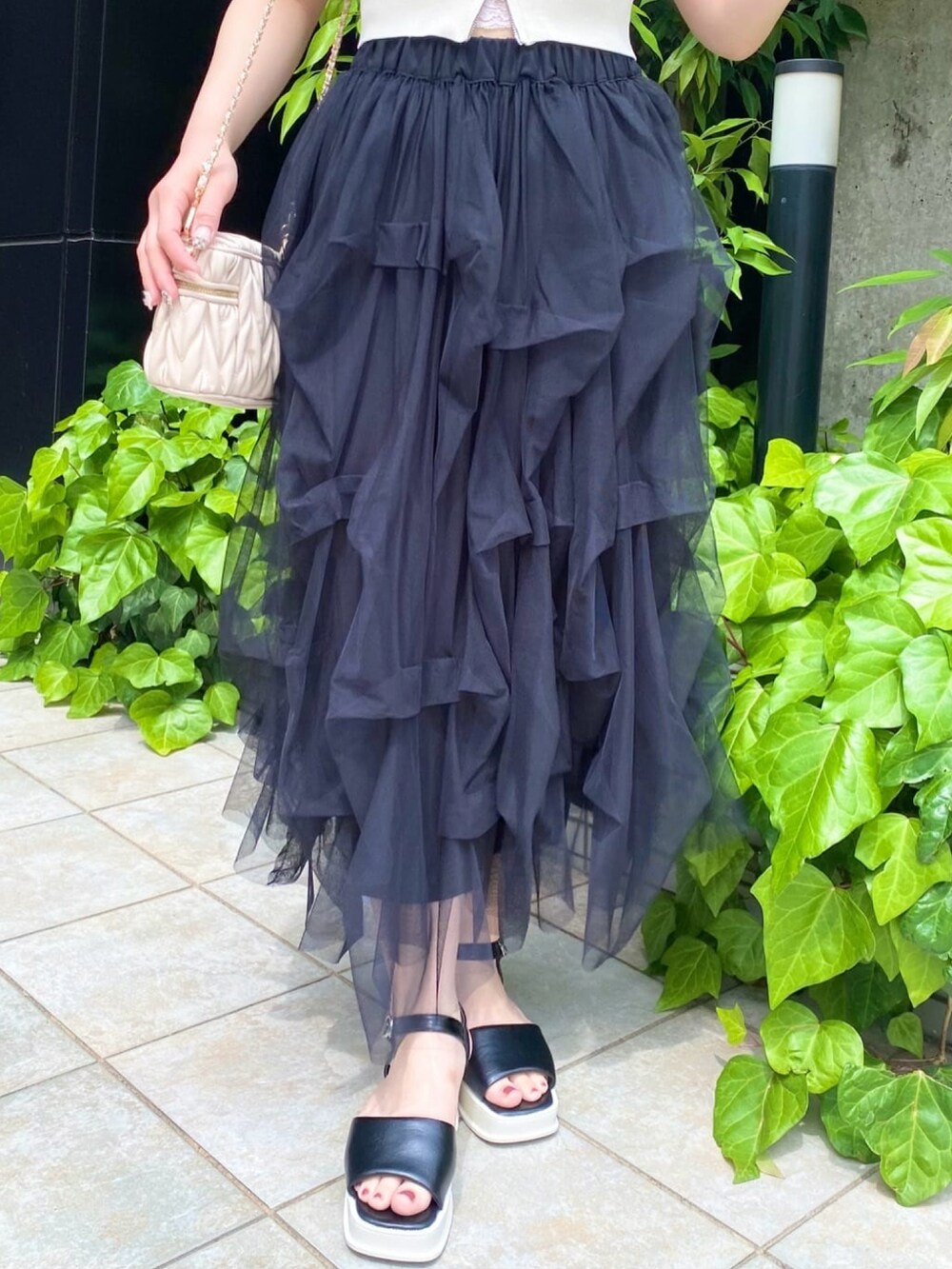 ブラック系のサンダル、ホワイト系のニット/セーター、ブラック系のスカートを着用したレディースの夏コーディネートの2枚目の写真