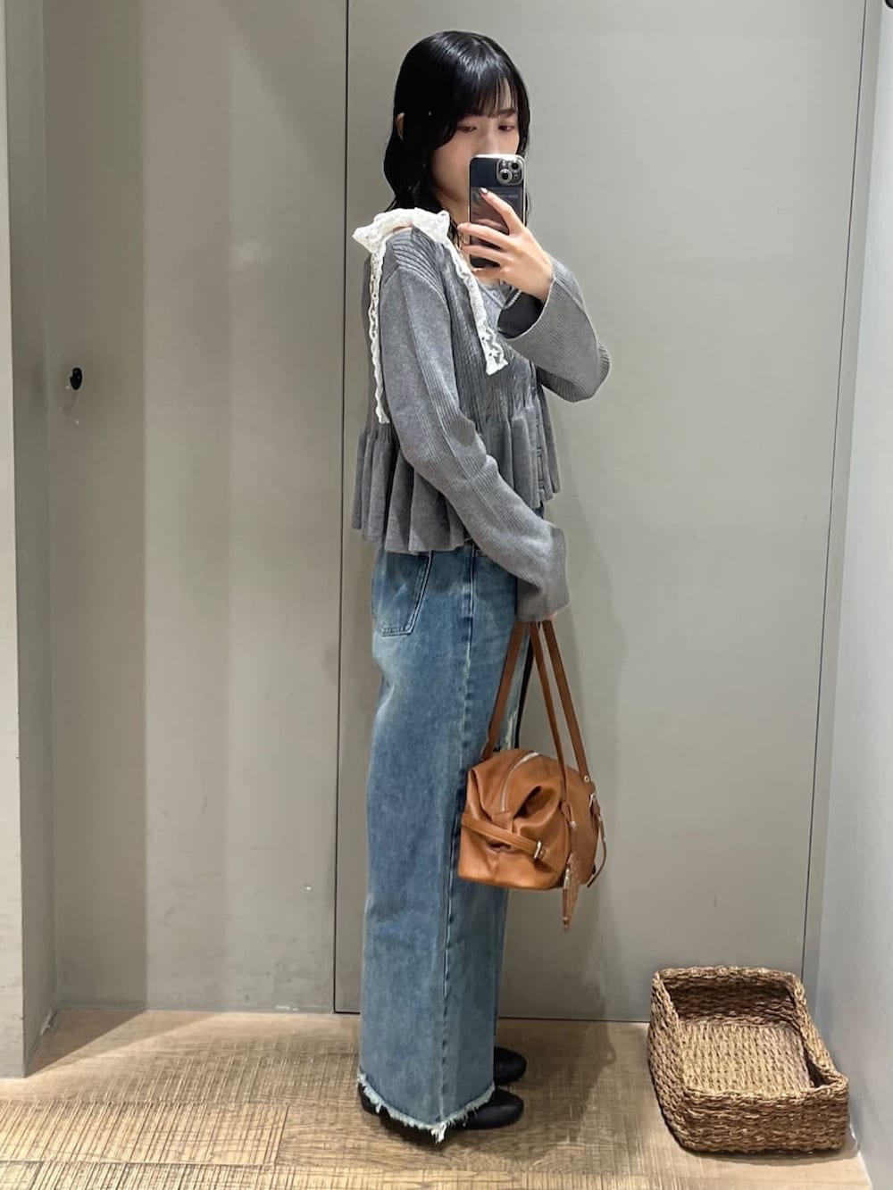 ブラウン系のボストンバッグ、グレー系のアンサンブル、ブルー系のデニムパンツを着用したレディースの秋コーディネートの2枚目の写真