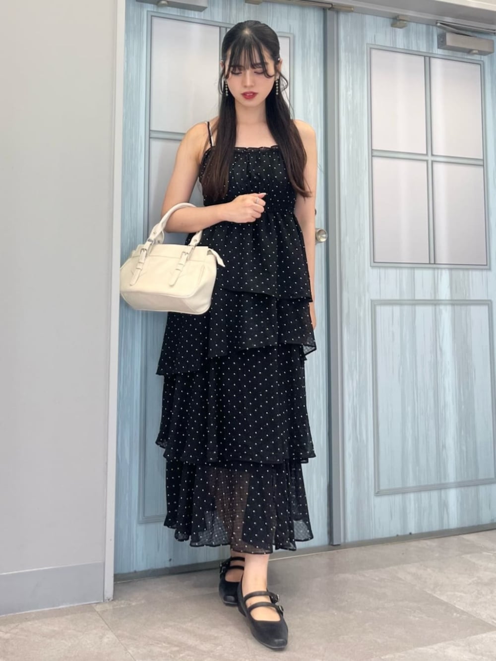 ブラック系のパンプス、ホワイト系のショルダーバッグ、ブラック系のワンピースを着用したレディースの夏コーディネートの2枚目の写真
