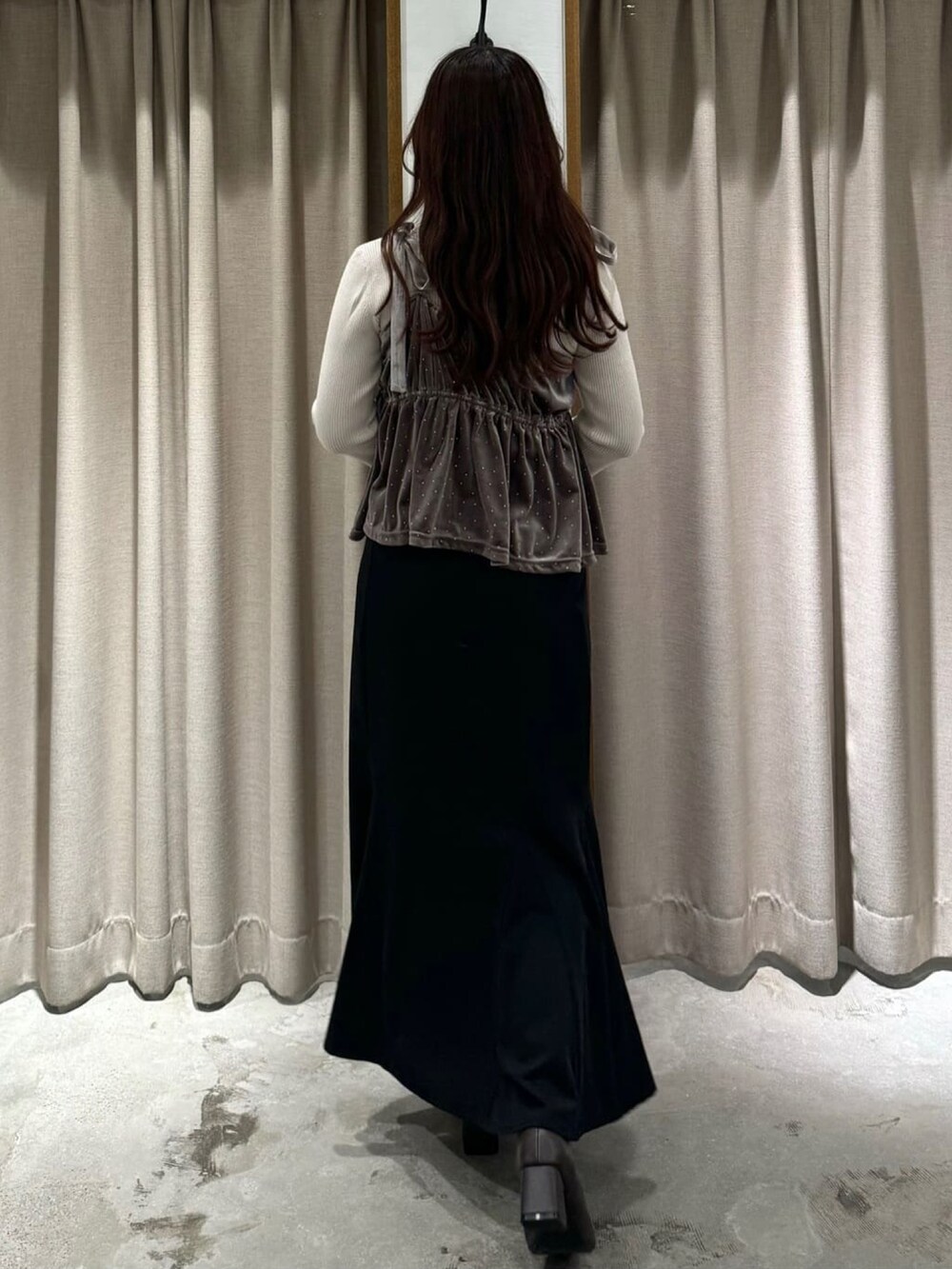 ピンク系のアンサンブル、ブラック系のスカートを着用したレディースの冬コーディネートの3枚目の写真