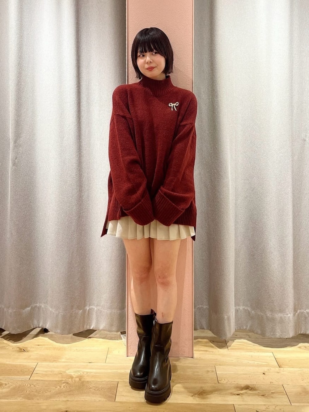 ブラック系のその他アウター、レッド系のニット/セーター、ホワイト系のスカートを着用したレディースの冬コーディネートの2枚目の写真