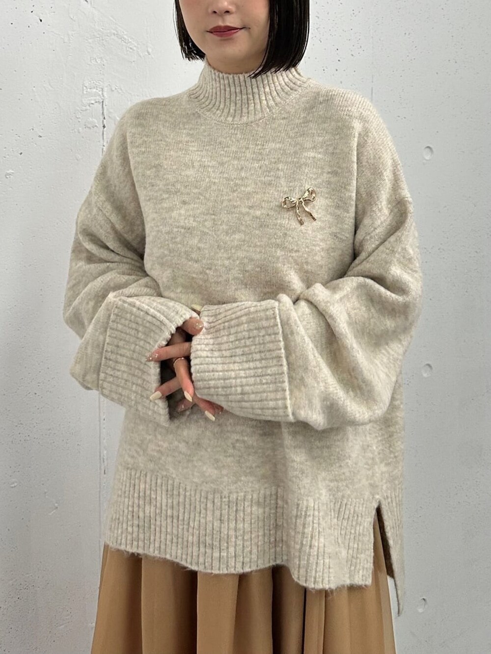 ホワイト系のニット/セーター、ブラウン系のスカート、ブラウン系のブーツを着用したレディースの冬コーディネートの3枚目の写真