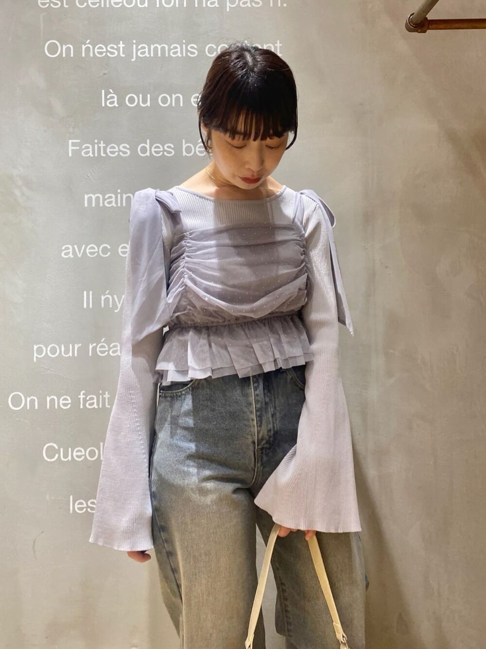 グレー系のアンサンブル、ブルー系のデニムパンツ、ホワイト系のショルダーバッグを着用したレディースの春コーディネートの3枚目の写真