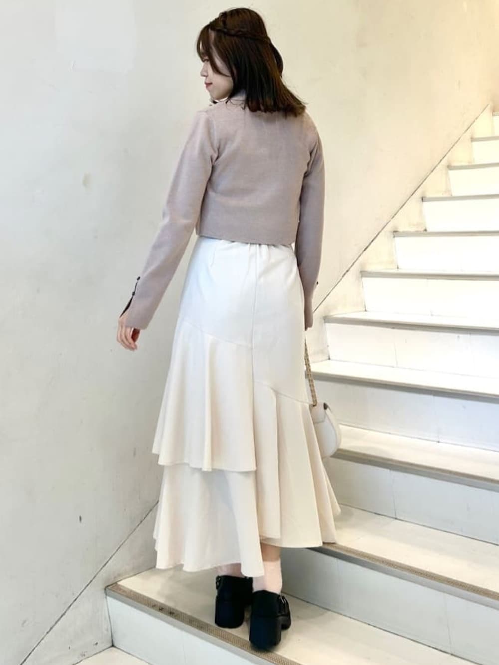 ピンク系のニット/セーター、ホワイト系のスカート、ホワイト系のショルダーバッグを着用したレディースの冬コーディネートの2枚目の写真