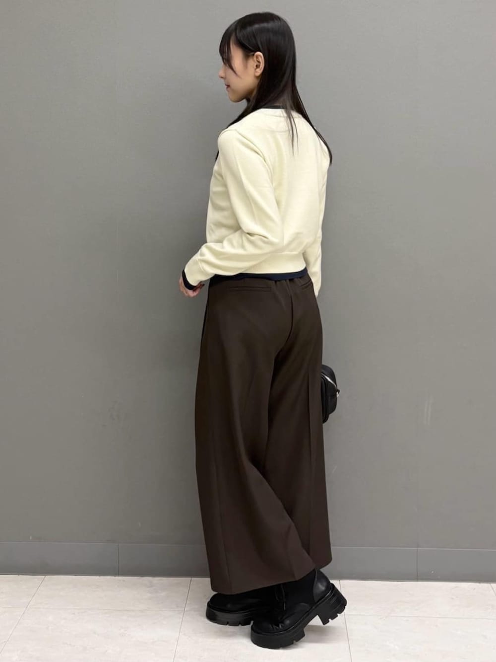 ホワイト系のカーディガン/ボレロ、ブラウン系のスラックス、ブラック系のボストンバッグを着用したレディースの秋コーディネートの3枚目の写真