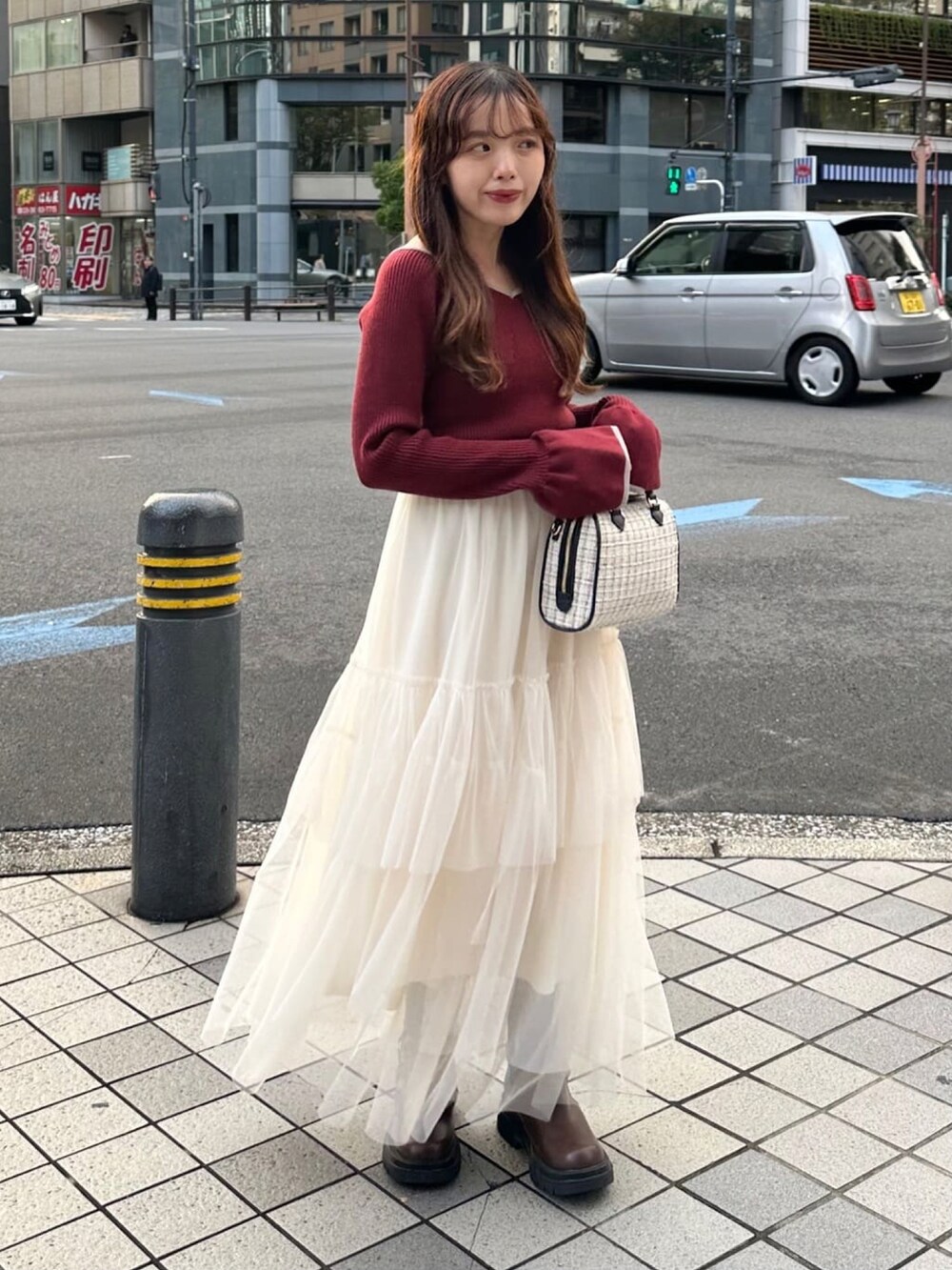 レッド系のニット/セーター、ブラック系のスカート、ホワイト系のボストンバッグを着用したレディースの冬コーディネートの2枚目の写真