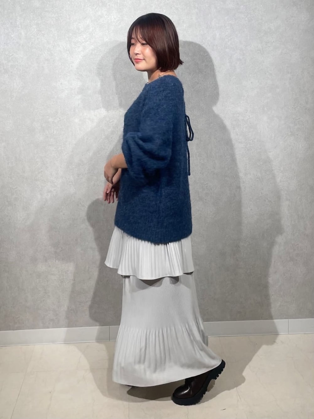 ブルー系のニット/セーター、グレー系のスカートを着用したレディースの秋コーディネートの2枚目の写真