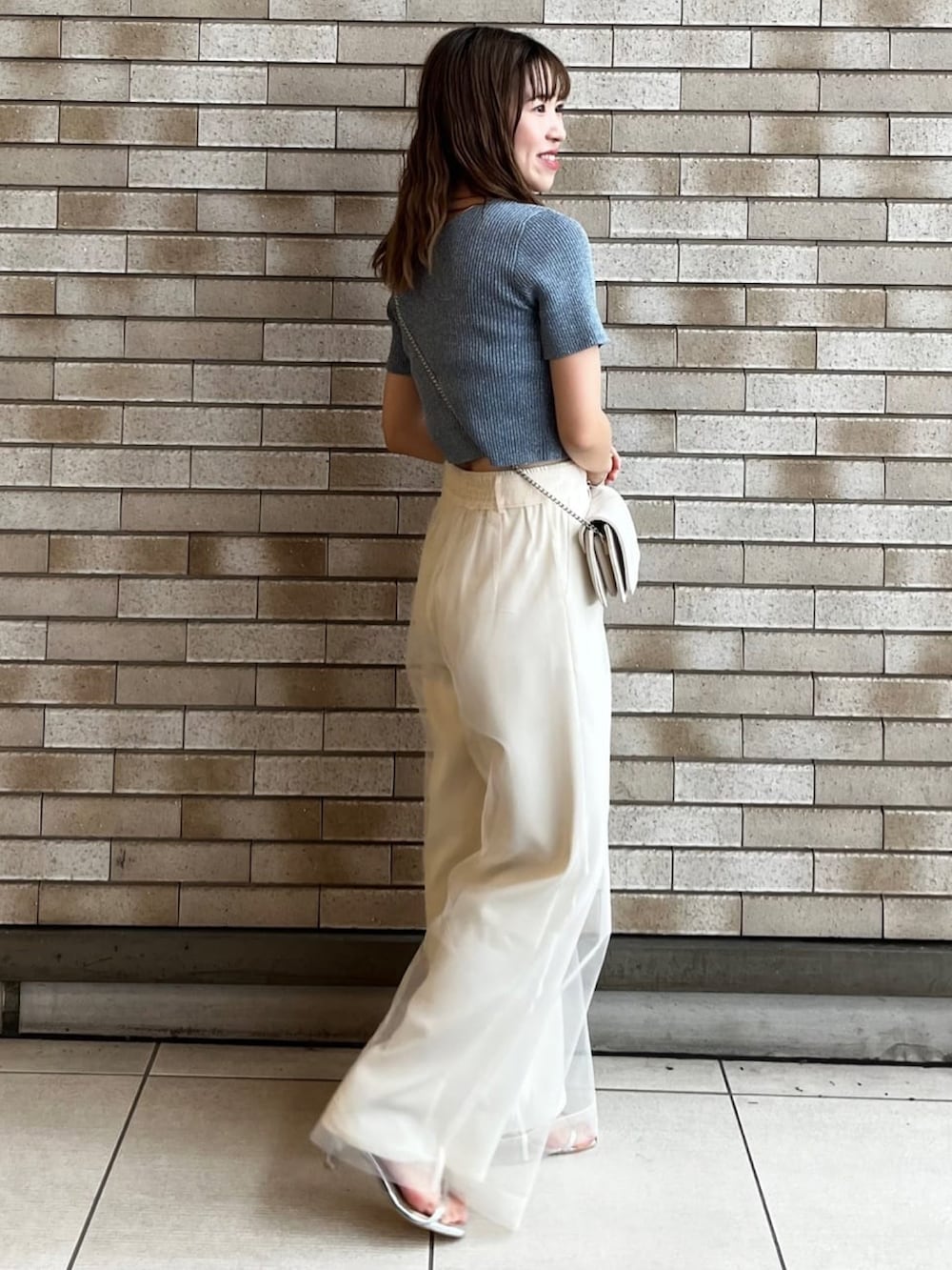 ブルー系のニット/セーター、ホワイト系のその他パンツ、グレー系のサンダルを着用したレディースの夏コーディネートの2枚目の写真