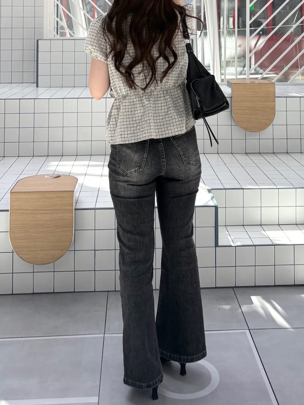 グレー系のデニムパンツ、ブラック系のサンダル、ブラック系のショルダーバッグを着用したレディースの夏コーディネートの3枚目の写真